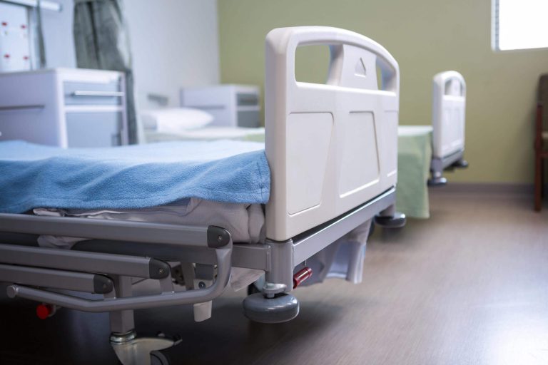 Krankenhausbett mit blauer Decke in einem hellen, modernen Raum für Patienten.