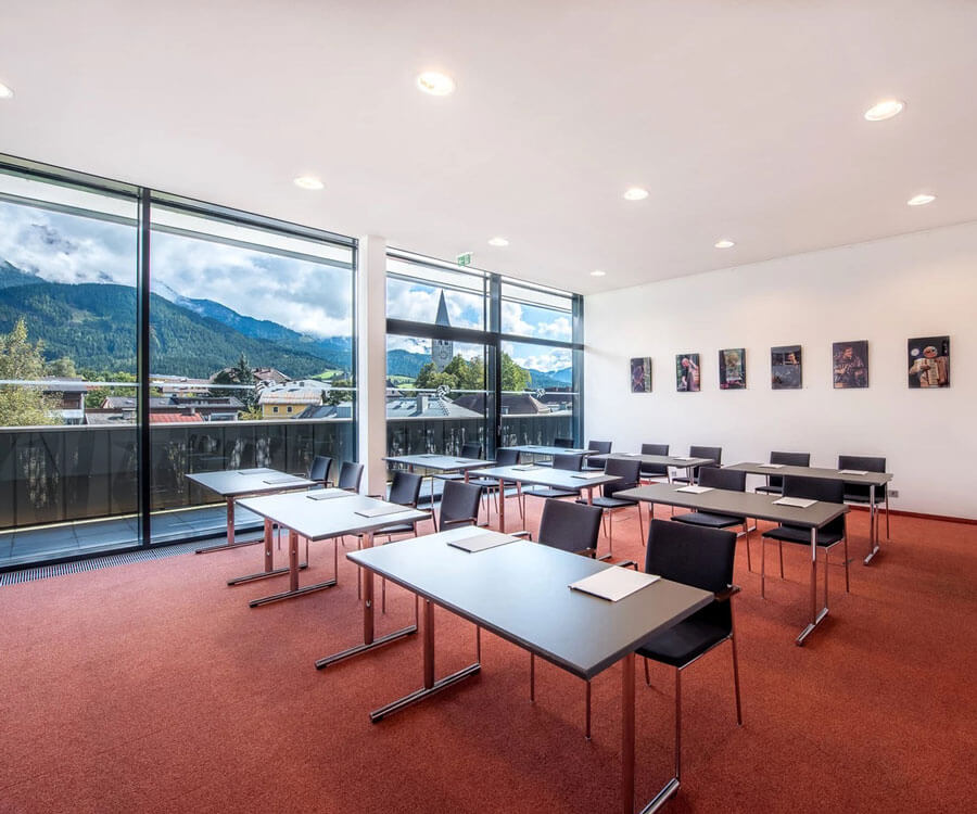 Moderne Seminarraum mit Tischen und Blick auf Berge und Kirche. Ideal für Hypertensiologie-Events.